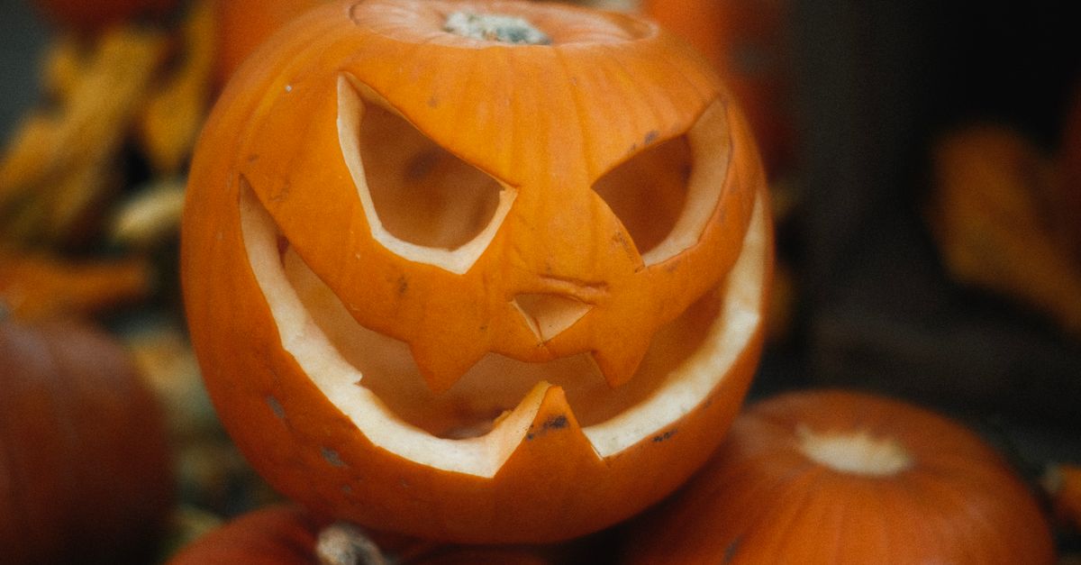 Close-up of a carved jack-o'-lantern surrounded by pumpkins, perfect for Halloween decor.